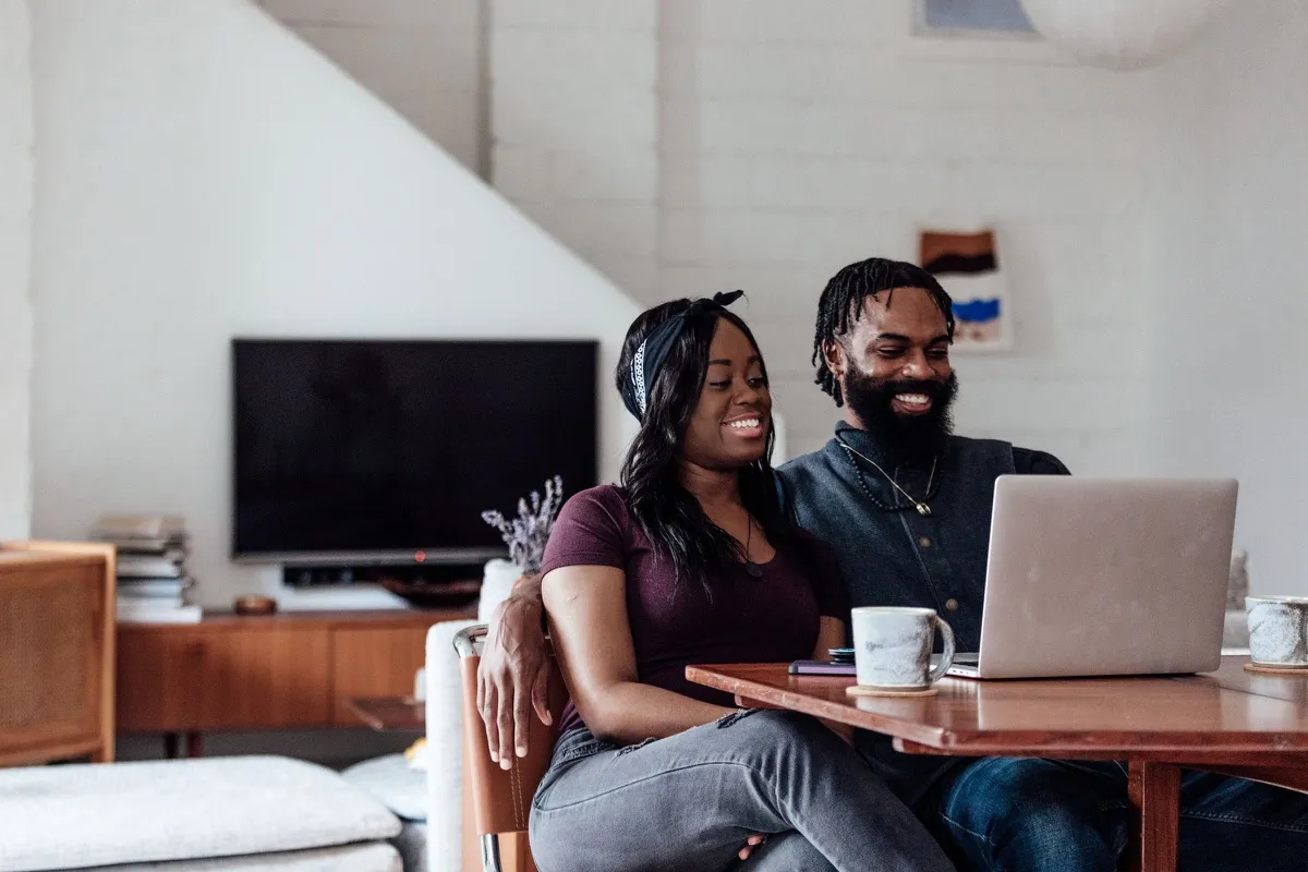 A couple on a sofa at home looking at a laptop together