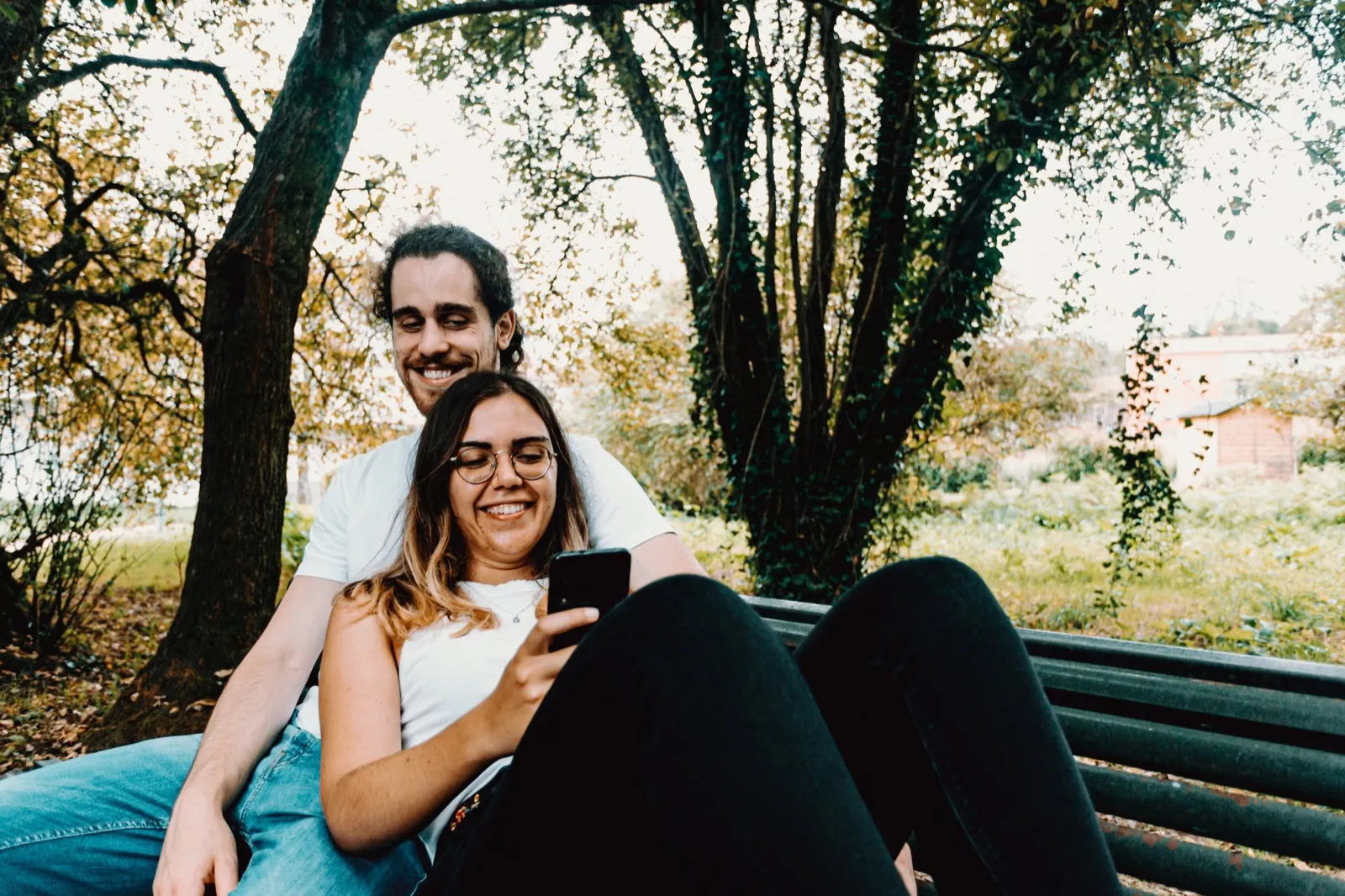 A couple on a park bench looking at a phone together