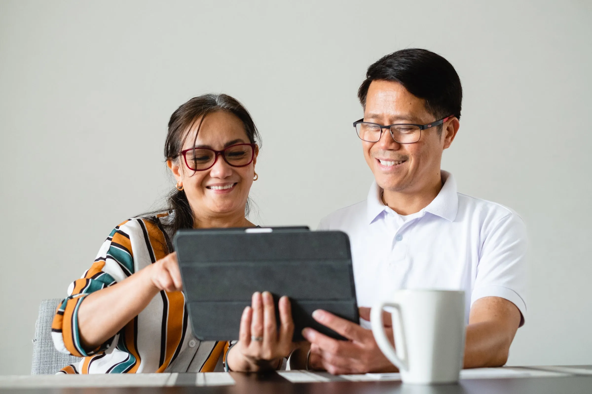 A smiling couple looking at a tablet together